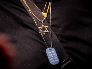 
Eine Frau trägt das Davidstern-Symbol und eine weitere Halskette mit der Aufschrift „Bring Them Home Now!“ während einer Kundgebung gegen den Antisemitismus auf dem Campus der George Washington University