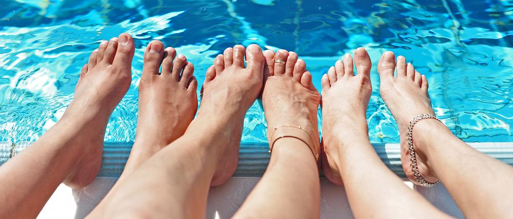 Drei Frauen halten in Berlin ihre Füße ins kühlende Wasser.