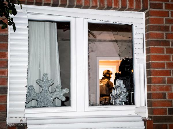 In Niedersachsen stehen Einsatzkräfte stehen hinter dem eingeschlagenen Fenster einer Wohnung. In zehn Bundesländern gab es bei dem Einsatz Durchsuchungen.
