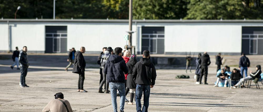 Asylsuchende laufen in der Erstaufnahmeeinrichtung Eisenhüttenstadt über einen Platz. 