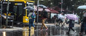 Menschen laufen mit Regenschirmen durch Berlin. (Symbolbild)