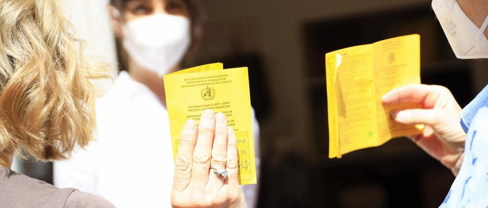 Zwei Frauen halten ihren Impfpass zur Kontrolle in die Luft.