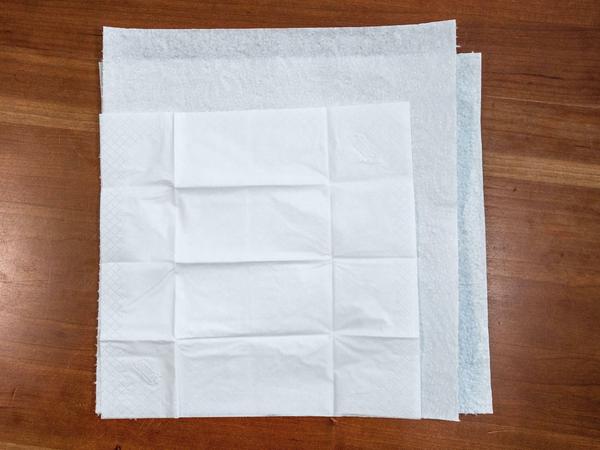 Breiten Sie ein Papiertaschentuch aus und legen Sie es auf die beiden ersten Blätter. Das Papiertaschentuch wird später die Innenseite Ihrer Schutzmaske sein. 