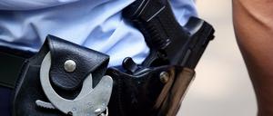 Symbolbild eines Polizisten mit Pistole und Handschellen.