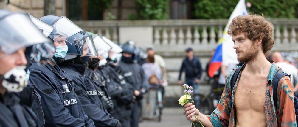 Ein Demonstrant hält bei einem Protest gegen die Corona-Maßnahmen vor der russischen Botschaft Blumen vor Polizisten.