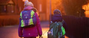 Zwei Schüler gehen am frühen Morgen auf dem Schulweg zu ihrer Grundschule. Künftig müssen sie auch bei Kontakt zu Infizierten nicht mehr in Quarantäne.
