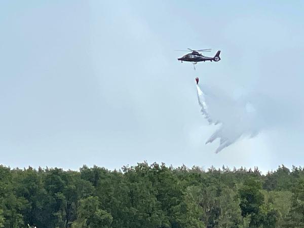 Ein Löschhubschrauber wirft Wasser über einem brennenden Waldstück nordwestlich von Berlin ab.