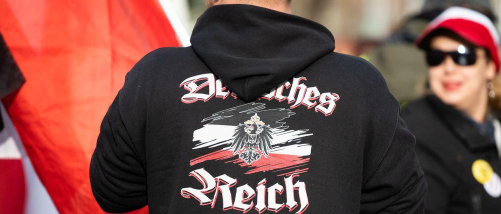 Ein Mann trägt einen Pullover mit dem Aufdruck "Deutsches Reich" bei einer Demonstration von Reichsbürgern.
