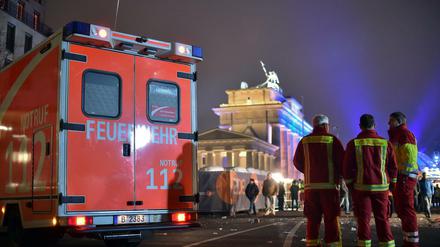 Einsatzkräfte der Berliner Feuerwehr stehen auf der Festmeile vor dem Brandenburger Tor. 