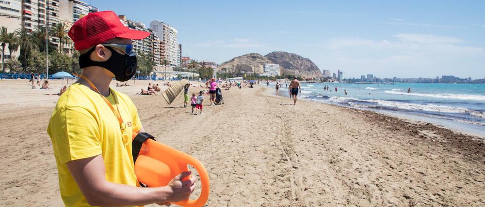 Ein Rettungsschwimmer mit Mundschutz am Strand von Alicante in Spanien.