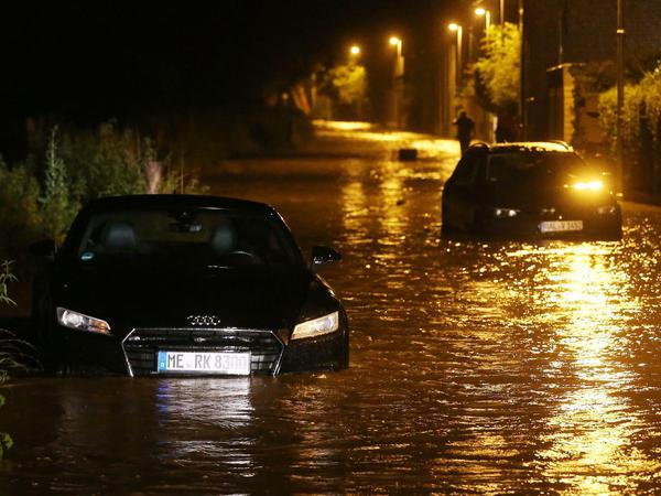 Zwei PKW stehen auf einer nach Starkregen überfluteten Straße in Erkrath in NRW