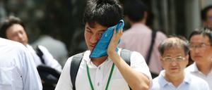 Ein Mann wischt sich den Schweiß aus seinem Gesicht in der sengenden Hitze Tokios.