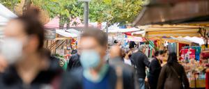 Menschen tragen Mund-Nasen-Bedeckungen und gehen in Berlin-Kreuzberg über den Markt am Maybachufer (Symbolbild).