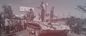 Unterstützer der sudanesischen Armee auf einem ausgebrannten Panzer der RSF-Miliz.