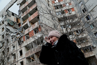 Eine Frau vor einem zerstörten Haus in Mariupol