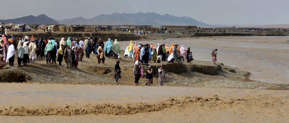Afghanen warten am 13. April 2024 nach einer Sturzflut infolge starker Regenfälle darauf, ein überschwemmtes Gebiet im Bezirk Spin Boldak in der Provinz Kandahar zu durchqueren. 