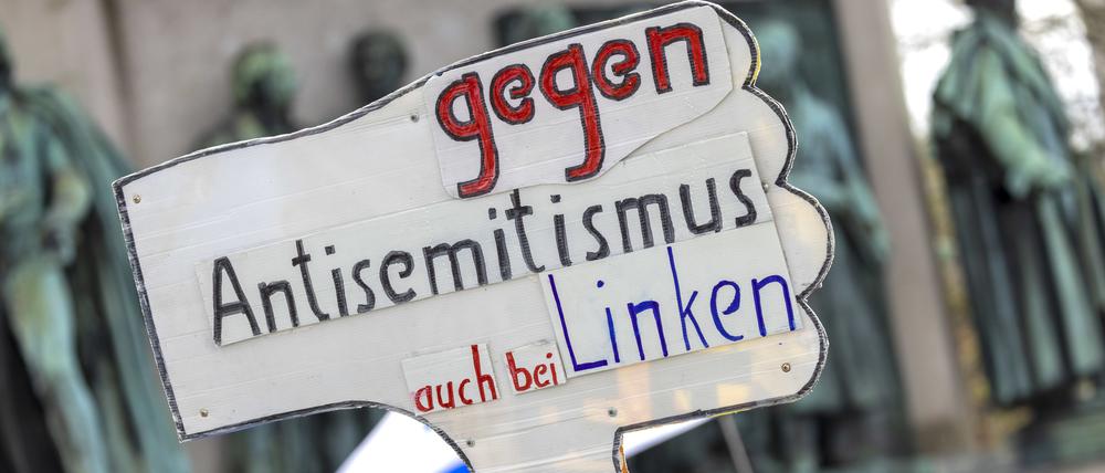 07.04.2024, Nordrhein-Westfalen, Köln: Ein Teilnehmer der Kundgebung hält ein Schild mit der Aufschrift „Gegen Antisemitismus auch bei den Linken“ hoch. 