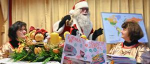 Der Weihnachtsmann steht nach der Ankunft im Weihnachtspostamt bei den Engeln, die seine Wunschzettel-Post öffnen und vorsortieren.