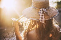 back view of blond woman with straw hat on sunset