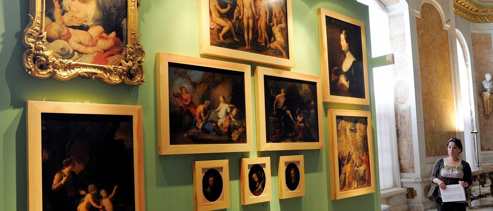 Eine Touristin betrachtet am Donnerstag in der Bildergalerie von Sanssouci in Potsdam die zehn vor einem Jahr zurückgegebenen Bilder, die seit 1945 als verschollen galten. Dank einer Spende des Lions Club konnten jetzt vier der zehn Bilder restauriert werden.