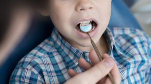 Ein Zahnarzt untersucht das Gebiss eines kleinen Jungen. (Symbolfoto)