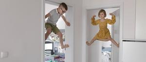 Zwei Kinder klettern den Türrahmen hoch. 