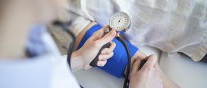 Close-up of doctor taking blood pressure of patient in medical practice
