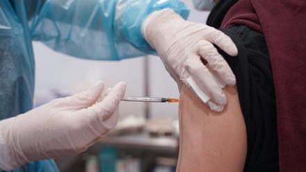 Ein junger Mann wird mit einer Booster-Dosis eines Corona-Impfstoffs im Impfzentrum in der Potsdamer Schinkelhalle gegen das Coronavirus geimpft.