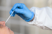 Eine Mitarbeiterin vom Gesundheitsamt hält ein Abstrichstäbchen eines Corona Tests in der Hand. 