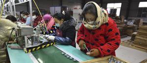 Gegen das kalte Wetter gewappnete Arbeiter montieren Lautsprecher in einer Elektronikfabrik im Bezirk Linquan in der zentralchinesischen Provinz Anhui. 