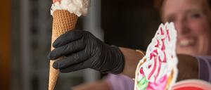 05.04.2020, Nordrhein-Westfalen, Bielefeld: Eine Verkäuferin hält eine Eiswaffel mit Latex-Handschuhen. Derzeit gibt es Kontaktbeschränkungen, die eine schnelle Ausbreitung des Corona-Virus bremsen sollen. Foto: Friso Gentsch/dpa +++ dpa-Bildfunk +++