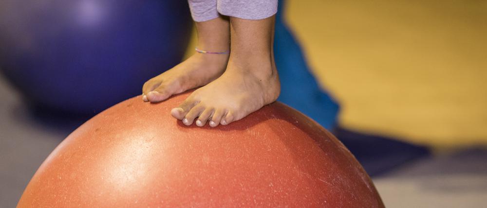 Ein Kind balanciert auf einem Gymnastikball.