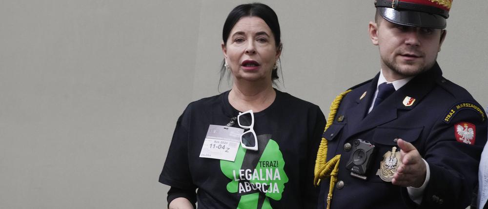 Eine Aktivistin, die ein T-Shirt mit der Aufschrift „Legale Abtreibung jetzt!“ trägt, wird von einem Wachmann zu einem Platz geführt, als sie an einer Parlamentsdebatte über die Liberalisierung des polnischen Abtreibungsgesetzes teilnimmt.