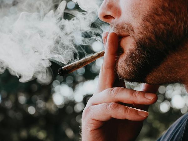 Ein Mann raucht zu unbestimmter Tageszeit einen Joint.