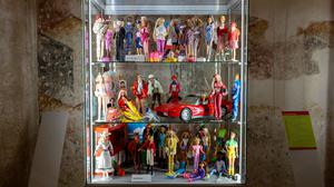 In einer Vitrine drängen sich zahlreiche Barbie-Puppen aneinander. 