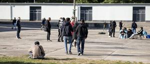 Asylsuchende laufen in der Erstaufnahmeeinrichtung Eisenhüttenstadt über einen Platz.