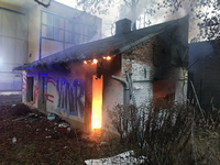 Feuerwehrleute müssen das Dach der in Brand geratenen Baracke öffnen, um Glutnester zu löschen.