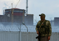 Ein Soldat mit einer russischen Flagge auf seiner Uniform hält vor dem Kernkraftwerk Saporischschja Wache (Symbolbild)