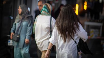 Eine Frau läuft in Teheran im Juli mit offenen Haaren eine Straße entlang.