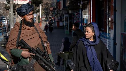 Ein Taliban-Kämpfer steht in Kabul in Afghanistan Wache, während eine Frau vorbeiläuft (Symbolbild). 