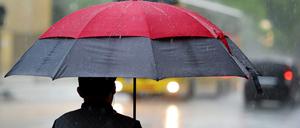 Ein Fußgänger geht mit einem Regenschirm am 31.05.2013 in Berlin auf der Rudi-Dutschke-Straße durch den Regen.