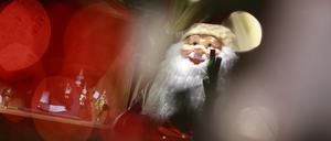 05.12.2023, Sachsen-Anhalt, Derenburg: Blick durch einen beleuchteten Weihnachtsbaum auf einen Weihnachtsmann in der Weihnachtsausstellung der Glasmanufaktur Harzkristall in Derenburg. 
