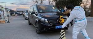 Ein Arbeiter in einem Schutzanzug entfernt inmitten des Ausbruchs der Coronavirus-Krankheit (COVID-19) in Peking, China, am 17. Dezember 2022 einen Kegel vor einem Leichenwagen vor einem Beerdigungsinstitut.