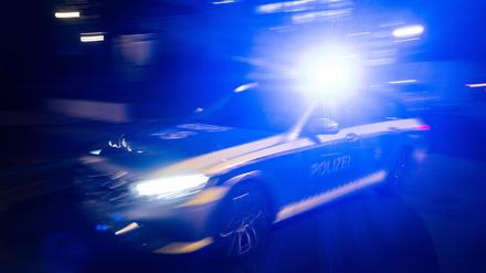 Ein Polizeifahrzeug fährt im Rahmen eines Fototermins mit Blaulicht an einem Gebäude vorbei.