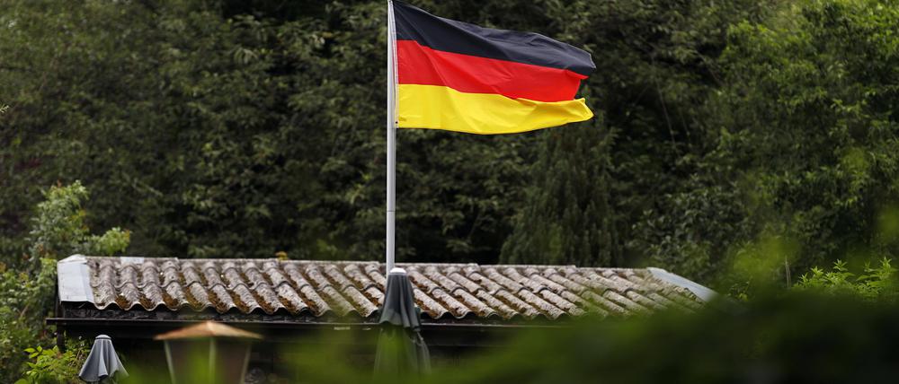 Eine Deutschlandfahne weht in einer Kleingartenanlage.