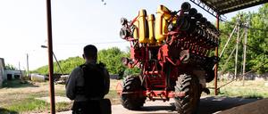 Ein landwirtschaftlicher Traktor wird von einem bewaffneten Security bewacht (Symbolbild)