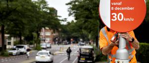 Ein Angestellter der Stadtverwaltung montiert ein Tempo-30-Schild an einer Straße in Amsterdam.