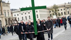 Gläubige tragen bei der Karfreitagsprozession der St. Marienkirche ein grünes Kreuz über den Berliner Bebelplatz.
