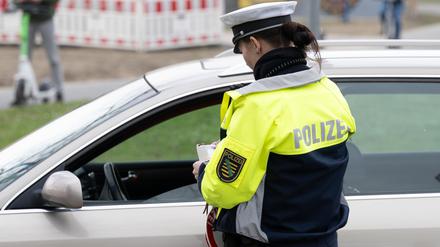 Eine Polizeiobermeisterin kontrolliert bei einer Verkehrskontrolle in Sachsen ein Fahrzeug.