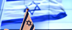 Eine Flagge Israels steht vor Beginn der Sitzung des Brandenburger Landtages vor der Kulisse eines Videobildschirms auf dem Rednerpult im Plenarsaal.